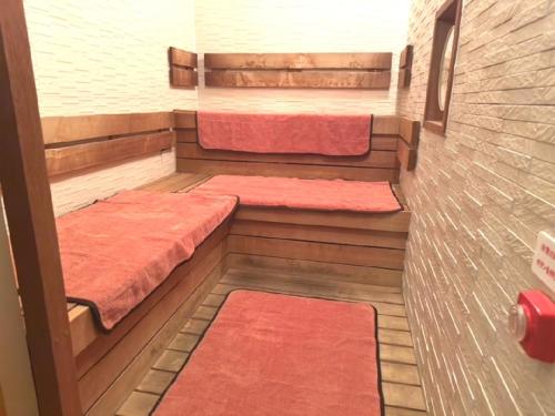 a small room with two beds and red rugs at Natural hot spring with sauna HOTEL GLAN Y's KOSHIGAYA in Koshigaya