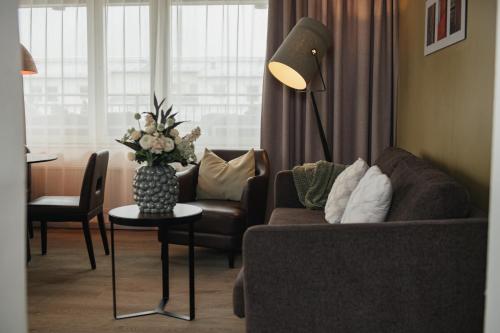 a living room with a couch and a vase of flowers at Quality Hotel Grand Falun in Falun