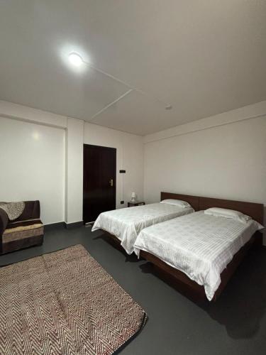 a bedroom with two beds and a couch and a rug at Kerphida B&B in Shillong