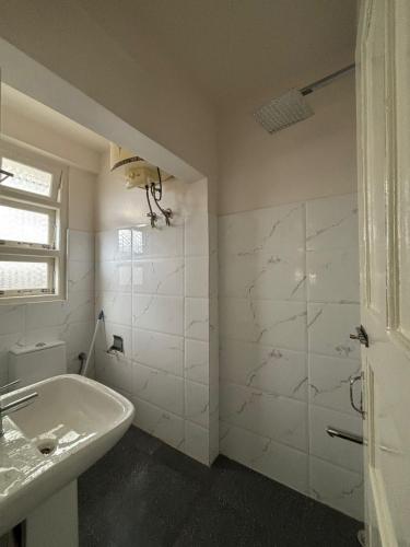 a white bathroom with a sink and a shower at Kerphida B&B in Shillong