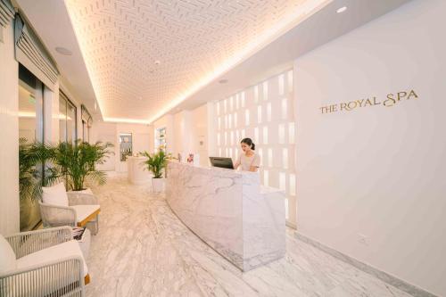 a woman standing at a counter in a lobby at Royal Saray Resort in Manama