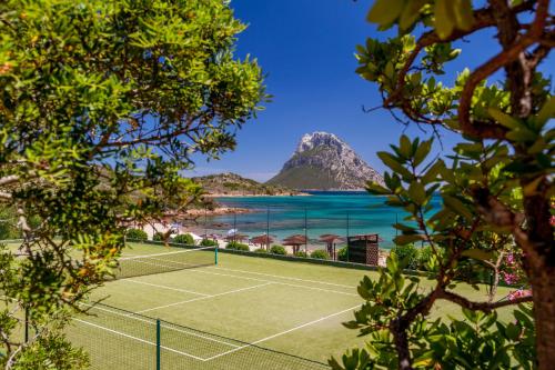 a tennis court on a beach with a mountain at Hotel Don Diego in Porto San Paolo