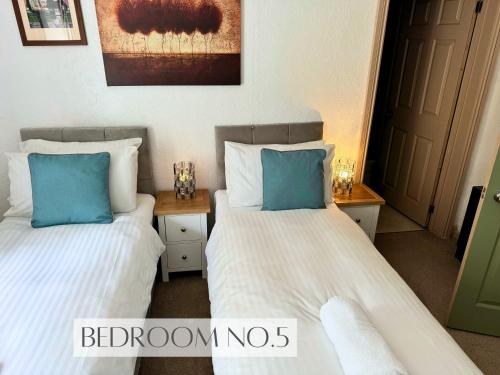 two beds in a room with blue pillows at Anchor's Drop in Blue Anchor