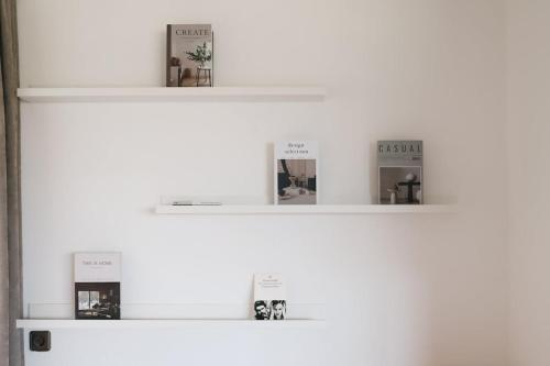 three shelves with books on a white wall at Guesthouse am See LOOM in Plescherken