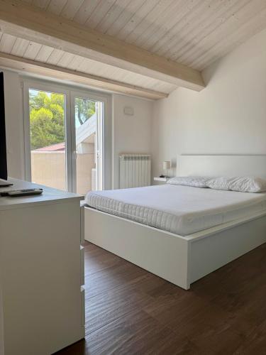 a white bedroom with a large bed and a window at Duplex da sogno nella posizione migliore di Giulianova Lido in Giulianova