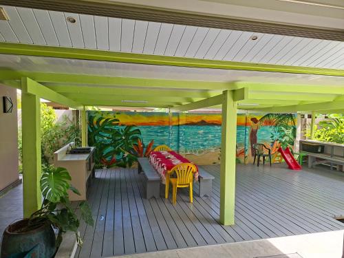 a deck with a table and chairs and a painting at Iolana's Beach house - Beautiful Home in Punaauia