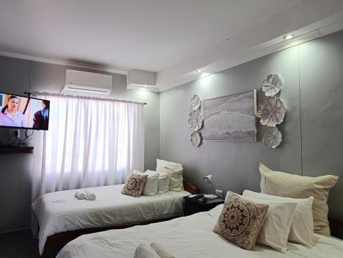 a hotel room with two beds and a flat screen tv at Guest House Bavaria in Rundu