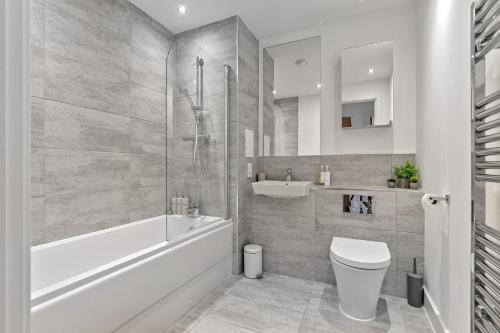 a bathroom with a tub and a toilet and a sink at MODERN & SPACIOUS AIRPORT APARTMENT, Free Parking, Juliet Balcony and Super King Bed in Luton
