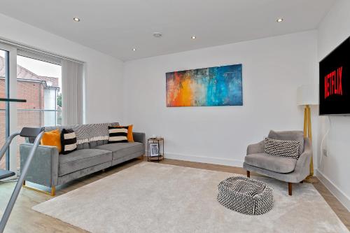 a living room with a couch and a chair at MODERN & SPACIOUS AIRPORT APARTMENT, Free Parking, Juliet Balcony and Super King Bed in Luton