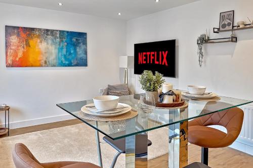 a dining room with a glass table and chairs at MODERN & SPACIOUS AIRPORT APARTMENT, Free Parking, Juliet Balcony and Super King Bed in Luton