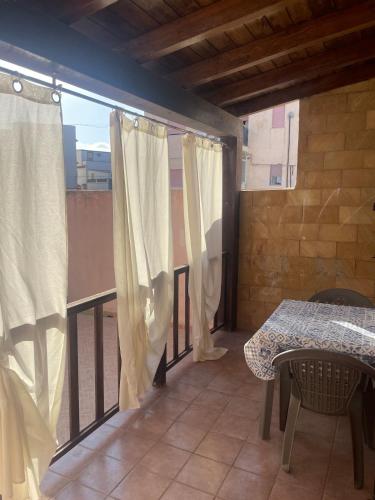 a room with a table and a balcony with curtains at Appartamento nel cuore di Lampedusa in Lampedusa