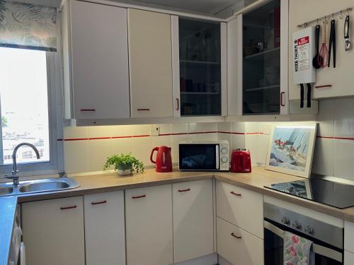 a kitchen with white cabinets and a microwave at Admirals Suite, Gibraltar in Gibraltar