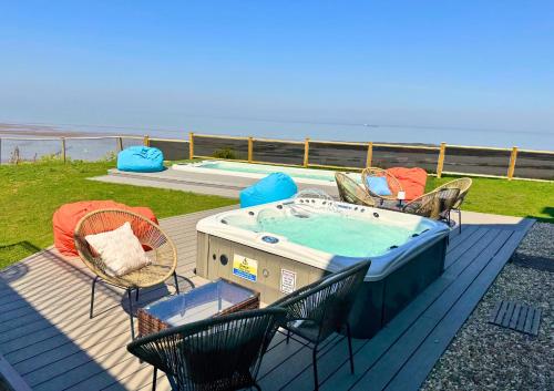 a deck with a hot tub and chairs and the ocean at Anchor's Drop in Blue Anchor