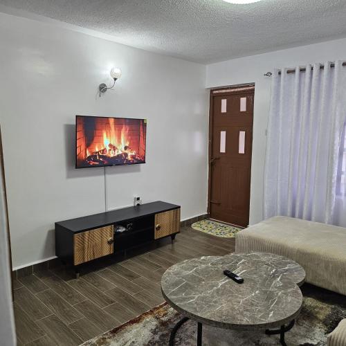 a living room with a bed and a table and a fireplace at Stays by Karen in Nanyuki