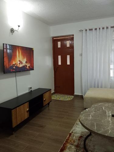 a living room with a couch and a tv on the wall at Stays by Karen in Nanyuki