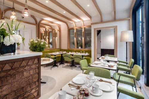 パリにあるHôtel Villa Madame - Saint-Germain-des-Présの白いテーブルと緑の椅子が備わるレストラン