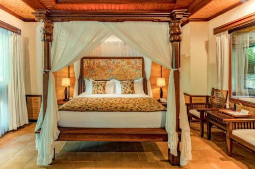 une chambre avec un lit à baldaquin dans une pièce dans l'établissement Sri Phala Resort & Villa, à anur