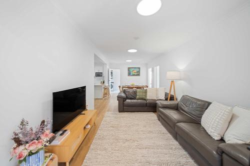 a living room with a couch and a flat screen tv at The Palms in Coolum Beach - Unit B in Coolum Beach