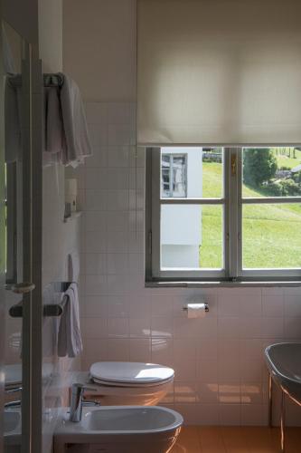 a bathroom with a toilet and a window at Hotel Tre Cime Sesto - Sexten in Sesto