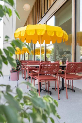 a row of tables and chairs under a yellow umbrella at HOOD Hotel in Geneva
