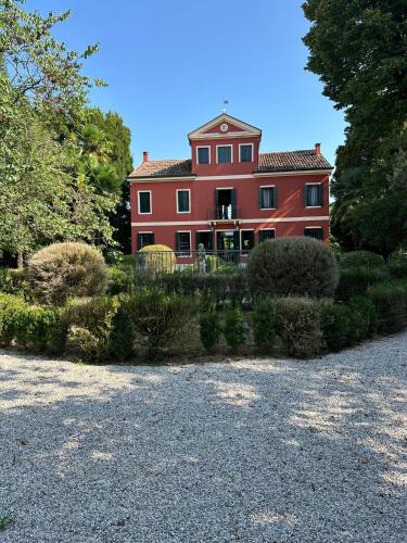a large red house with a lot of bushes at Osteria Locanda Veneta in Mirano