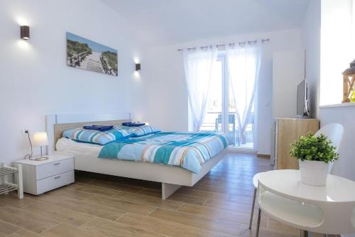 a white bedroom with a bed and a table at Steinhaus Mediterra mit Pool & Meerblick - Lukoran, Insel Ugljan bei Zadar in Lukoran