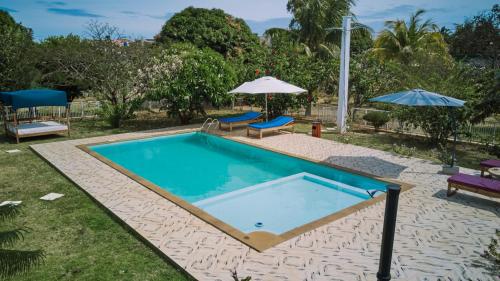 a swimming pool with two chairs and an umbrella at Villa SAIDIA climatisée avec PISCINE in Diego Suarez