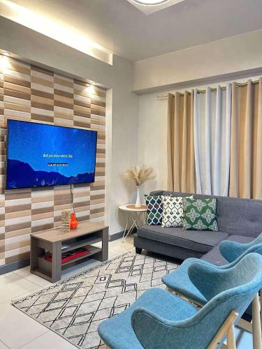 a living room with a couch and a flat screen tv at Adi Hideaway Staycation at Camella Northpoint 2 Bedroom in Davao City