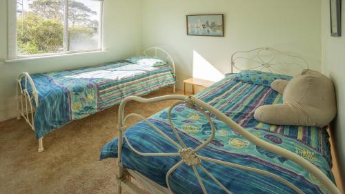 a bedroom with two twin beds and a bed with a chair at The Fibro Majestic in Bawley Point
