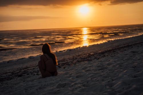 a woman sitting on the beach watching the sunset at ARYA Sumba Resort - Kodi in Tambolaka