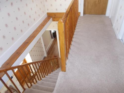 a stairway with a wooden railing and a stair case at Inveravon Holiday Home in Dufftown