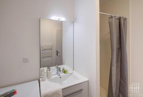 une salle de bains blanche avec un lavabo et un miroir dans l'établissement Petunia - Maison - Parking, à Fondettes