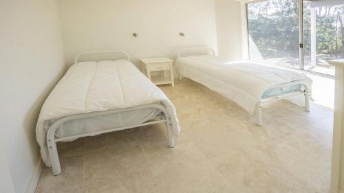 two beds in a white room with a window at Anchor at Bawley in Bawley Point