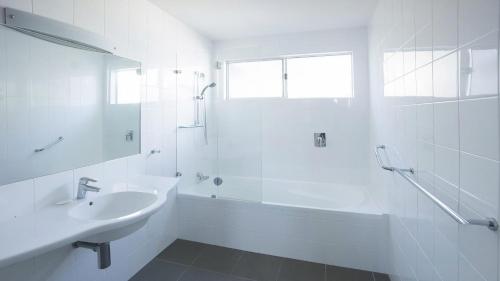 a white bathroom with a sink and a bath tub at Anchor at Bawley in Bawley Point