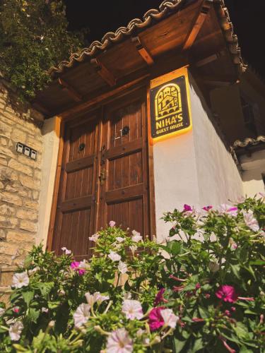 a building with a wooden door with a sign on it at Nika's Guest House in Berat