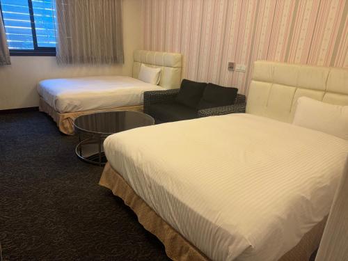 a hotel room with two beds and a couch at Fairy Tale City Motel in Hualien City