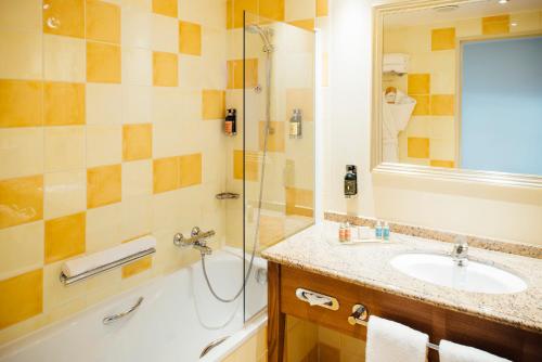a bathroom with a sink, mirror, and bathtub at Dream Castle Hotel Marne La Vallee in Magny-le-Hongre