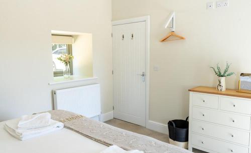 a white bedroom with a bed and a window at Blacksmiths in Brauncewell