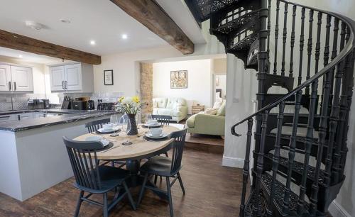 a kitchen and living room with a table and a spiral staircase at Blacksmiths in Brauncewell