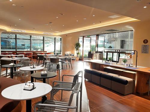 a restaurant with tables and chairs and windows at Citadines Gongbei Zhuhai in Zhuhai