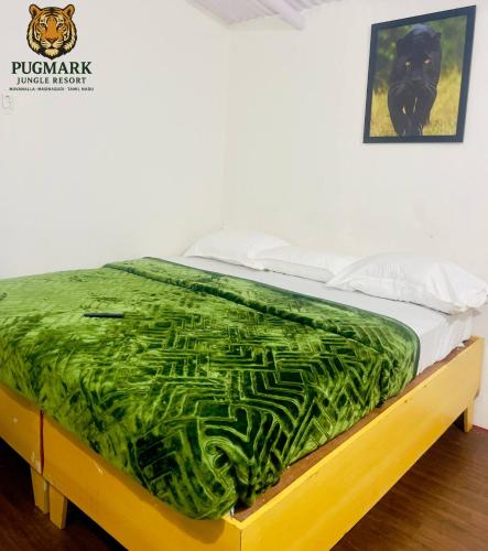 a bed with a green blanket on top of it at Pug Mark Jungle Resort - Masinagudi in Masinagudi