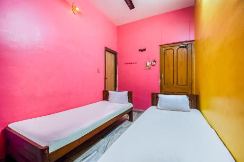 two beds in a room with pink and yellow walls at Hotel O Roshan in Āsansol