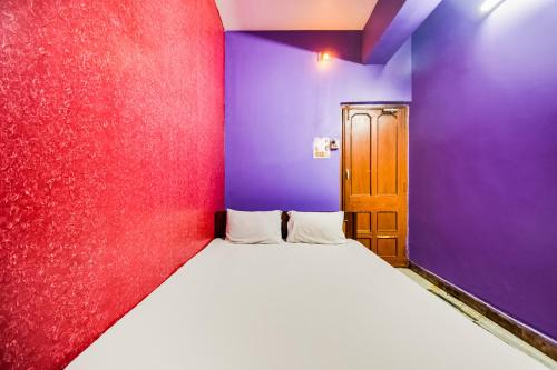 a small room with a bed with purple and purple walls at Hotel O Roshan in Āsansol