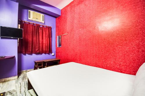 a bedroom with red and purple walls and a bed at Hotel O Roshan in Āsansol