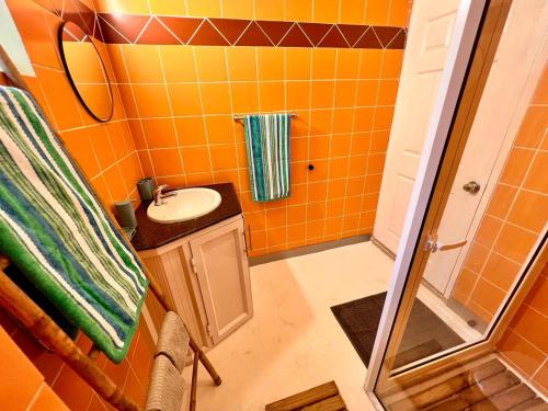 a small orange bathroom with a sink and a shower at Beach Villa Coco in Palmar