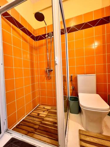 an orange tiled bathroom with a toilet and a shower at Beach Villa Coco in Palmar