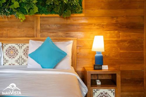 a bedroom with a bed with a blue lamp on a table at Taman Prabhawa by Bukit Vista in Sukawati