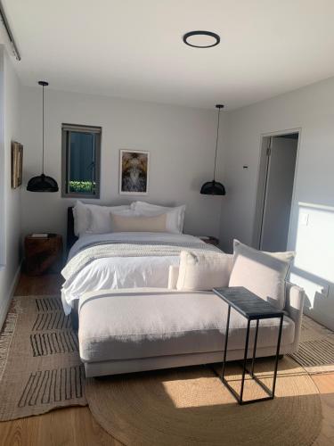 a bedroom with a large white bed and a chair at Tide and Timber Luxury Guesthouse in Hermanus