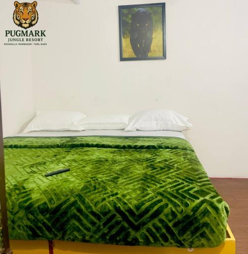 a bed with a green blanket on top of it at Pug Mark Jungle Resort - Masinagudi in Masinagudi