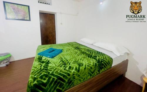 a bed with a green cover on top of it at Pug Mark Jungle Resort - Masinagudi in Masinagudi